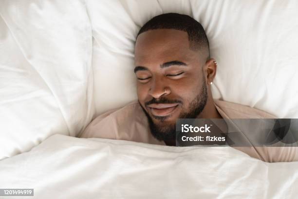 Calm Biracial Man Sleeping Seeing Pleasant Dreams Stock Photo - Download Image Now - Sleeping, Men, Bed - Furniture