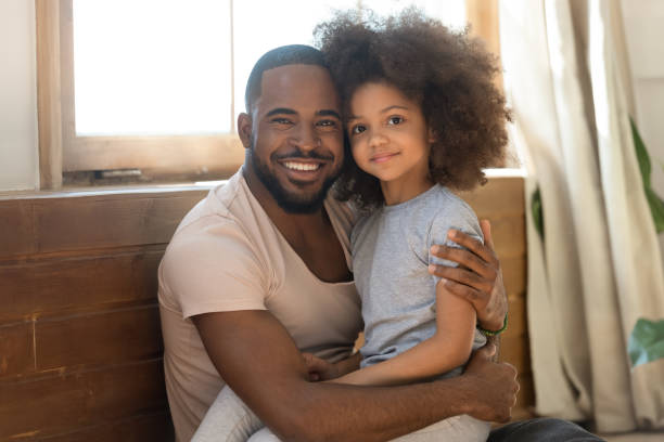 istock Smiling biracial dad and preschooler daughter hug looking at camera 1201494939
