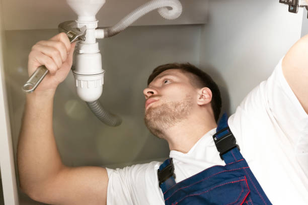 istock man plumber in uniform fixing the sink pipe in the kitchen with adjustable spanner in his hand looks concentrated professional plumbing repair service 1201496235