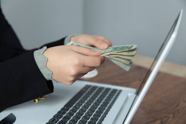 istock woman hand money with computer screen 1201497475