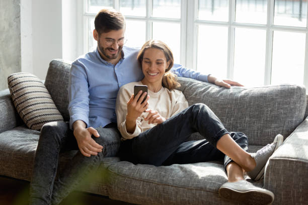 istock Happy millennial couple relax on couch using cellphone 1201499326