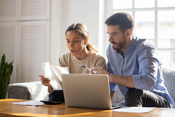 istock Focused young couple manage finances paying bills online 1201499331