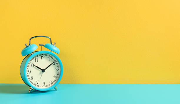 istock Alarm clock on turquoise yellow background. Front view. 1201500737