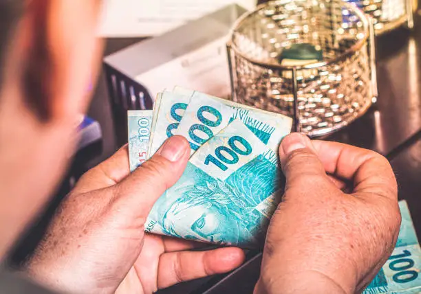 Photo of Brazilian Real, BRL. Woman, money, money, hand. Woman holding bank notes of Brazilian currency.