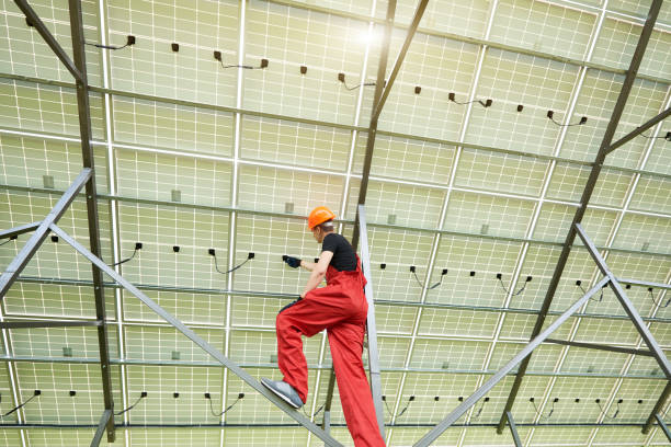istock Young electrician connecting electrical cables inside the lit by sun solar modules 1201507159