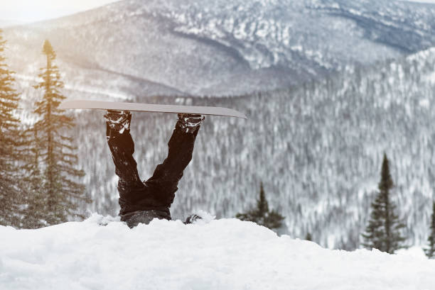 Snowboarding. Snowboarder feet sticking out of the snow on a snowy mountains background. protruding stock pictures, royalty-free photos & images
