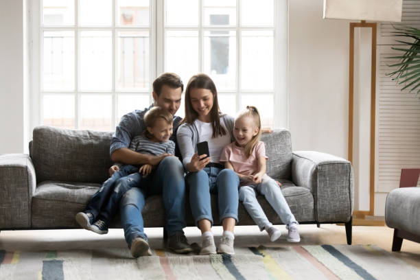 istock Happy parents with kids relax at home using cellphone 1201510259