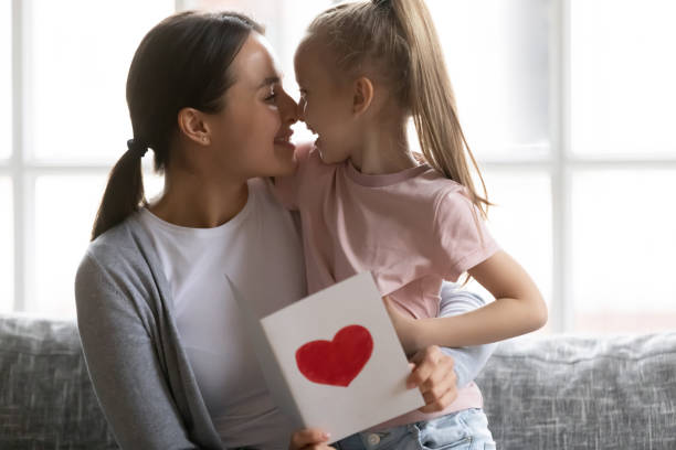 istock Cute little daughter greeting mom with handmade postcard 1201510281