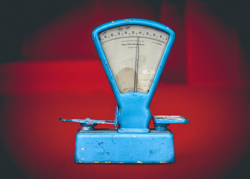 Vintage weathered blue food weighing scale on red background, souvenir of the communism era in Poland