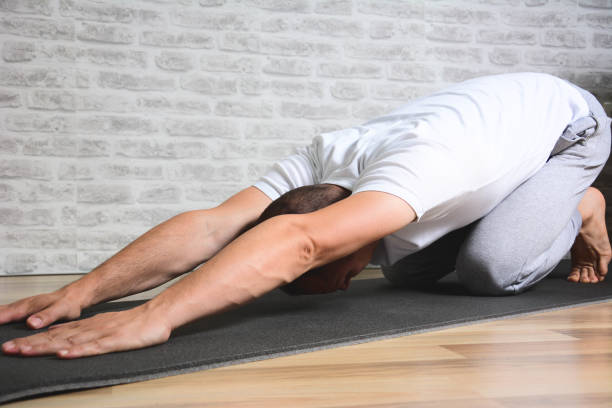 istock Male performing yoga on exercise mat at gym 1201510697