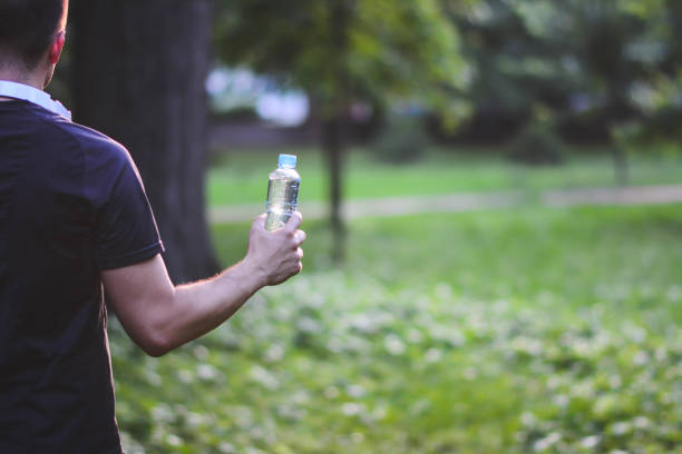 istock Man Drinking Water outdoor in park with sun. 1201510827
