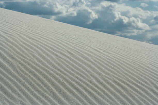 Fermez-vous vers le haut de la dune blanche avec des modèles d'onde et le ciel bleu clair au monument national de sables blancs - Photo