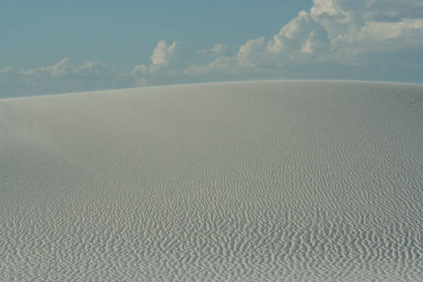 Fermez-vous vers le haut de la dune blanche avec des modèles d'onde et le ciel bleu clair au monument national de sables blancs - Photo
