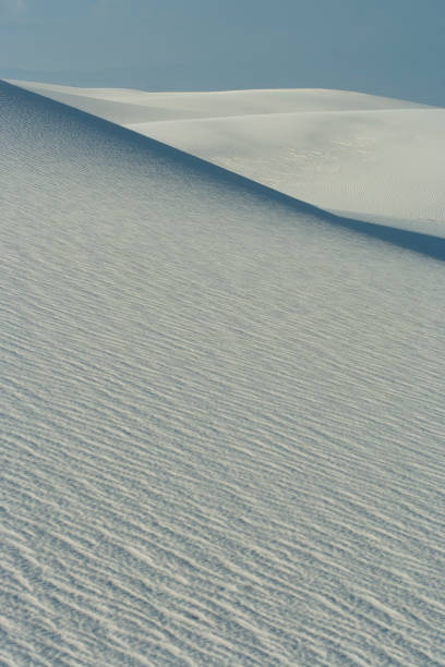 Fermez-vous vers le haut de la dune blanche avec des modèles d'onde et le ciel bleu clair au monument national de sables blancs - Photo