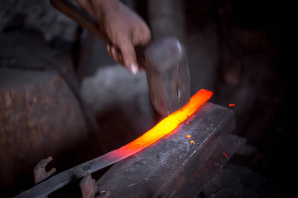 istock Blacksmith's hands at work. In one hand a hammer, in the other a workpiece of hot metal. Master methodically hammer hits the anvil. An example of the hard work of ancient crafts. 1201519521