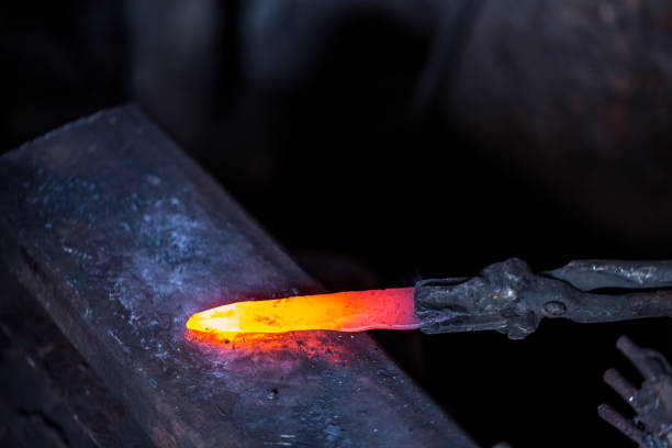 istock In a blacksmith's workshop. Blacksmith in one hand hold a workpiece of hot metal on a anvil. An example of the hard work of ancient crafts. 1201519549