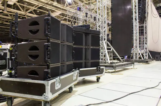 Photo of Flight cases with line array speakers. Stage, trusses, led screen and sound speakers background. Installation of professional concert equipment.