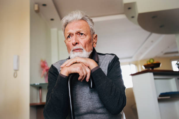 istock Thoughtful elderly man sitting alone at home with his walking cane 1201520751