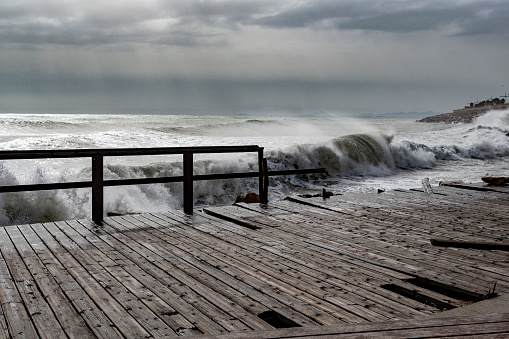Big waves are splashing at the pier at a stormy day.