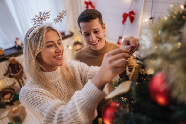 istock Cheerful young couple decorating a Christmas tree 1201522190