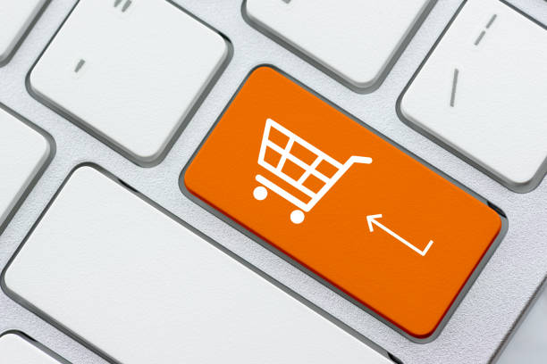 オンラインショッピング/eコマースと小売販売の概念:チェックアウトのためのホワイトバスケット、ラップトップキーボード上のショッピングカートのシンボルは、顧客がインターネットを� - catalog internet e commerce customer ストックフォトと画像
