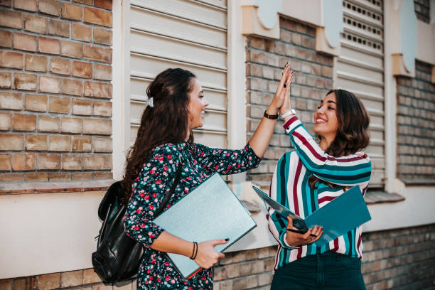 istock Happy Female students giving five to each other during friendly collaboration on studying project, while standing in the street 1201524993