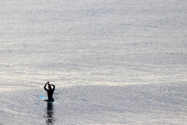 istock Woman sitting on a surfboard in sea 1201529255