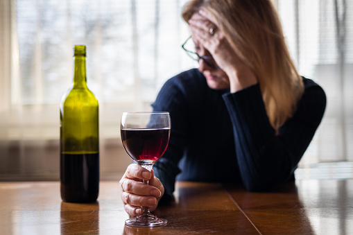 Mujer triste solitaria bebiendo vino tinto en casa photo