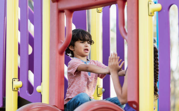 istock Hispanic boy and sister playing patty cake on playground 1201536895