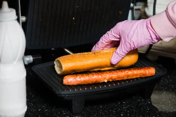 Photo of bartender making french hot dog on grill