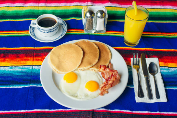 istock Tasty breakfast with pancakes, fried eggs and bacon on table. 1201541965