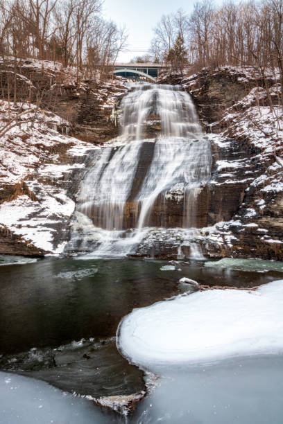 istock Multi tiered waterfall cascading down rocks in a snowy winter wonderland scene. 1201542813