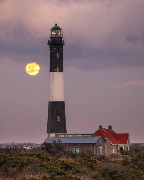 istock Full moon rising behind a tall stone lighthouse. 1201543611