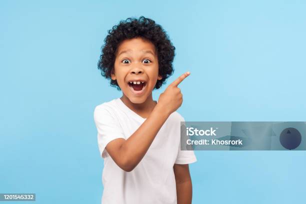 Wow Look Advertise Here Portrait Of Amazed Cute Little Boy With Curly Hair Pointing To Empty Place Stock Photo - Download Image Now