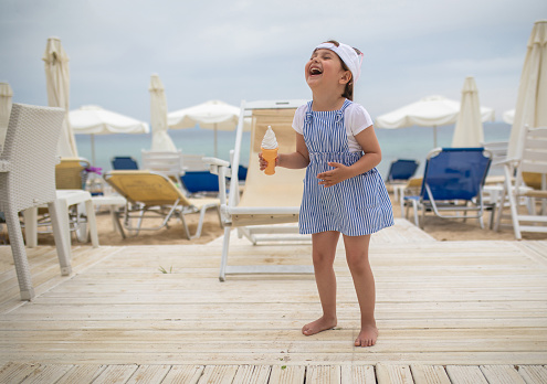 Beautiful innocent child holding an ice cream toy while enjoying the day on a beach.