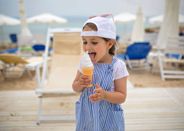 istock Cute child licking an ice cream on a beach 1201547057