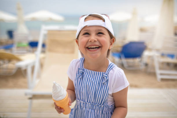istock Cute ecstatic child holding an ice cream while laughing on a beach 1201547133