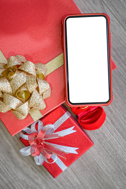 istock White blank screen of phone with gift boxes and ring on wooden background. 1201551057