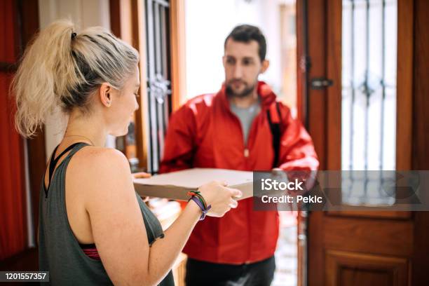 Delivery Person Giving Pizza Box To Woman At Doorstep Stock Photo - Download Image Now