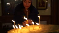 istock Asian woman praying and lighting up a candle in church 1201558341