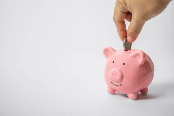 Hand Putting Coin Into Piggy Bank stock photo