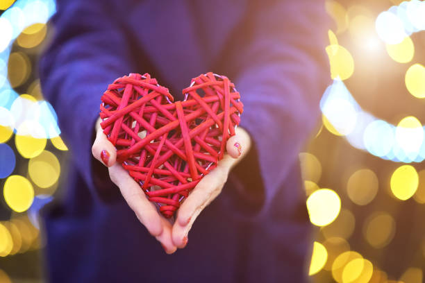 gran corazón rojo en las manos sobre un fondo borroso - valentines day teenager passion romance fotografías e imágenes de stock