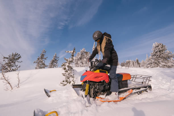 istock Beautiful woman driving snowmobile in winter forest. 1201570868