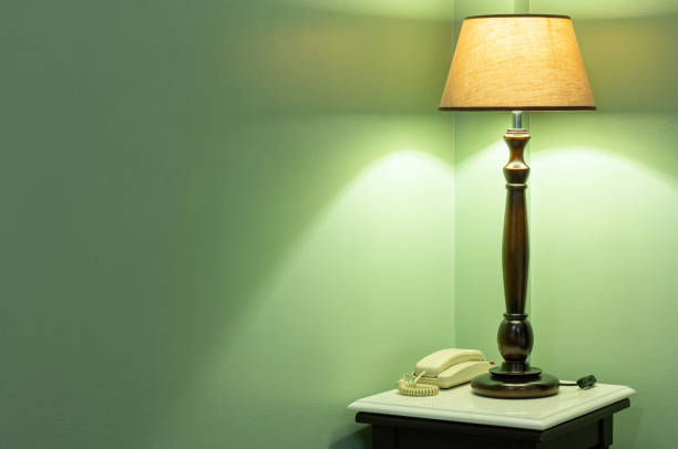 A lamp on a table next to a bed at night time