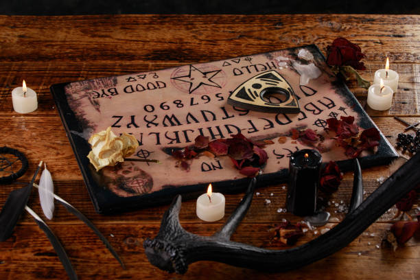 istock Talking board and planchette, also known as Ouija board, used for communicating with the dead and other spirits. The atmosphere of black art with candles and horns of the animal. 1201576263