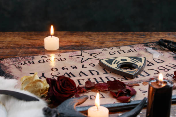 istock Mystic ritual with Ouija and candles. Devil's board concept, black magic or fortune telling rite with occult and esoteric symbols. 1201576426