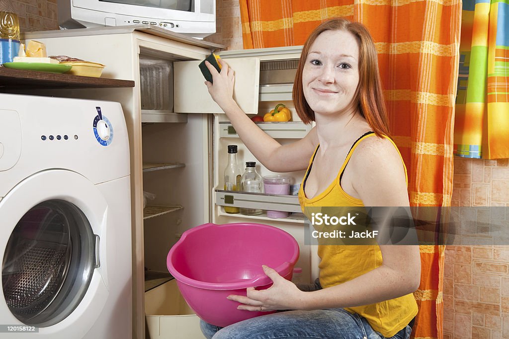 Donna pulizia del frigorifero - Foto stock royalty-free di 20-24 anni