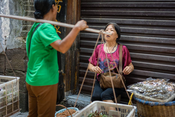 Feng Huang, China - August 2019 : Women talking, chatting and having friendly conversation on the street in theOld Town, FengHuang city, Hunan Province