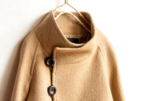 istock beige wool coat hanging on clothes hanger on white background. 1201591984