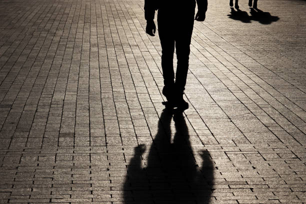 silueta y sombra de un hombre solitario caminando hacia una pareja en una calle - focus on shadow shadow women silhouette fotografías e imágenes de stock